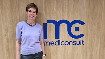 Laura Virros seisoo puulta näyttävän seinän edessä. Seinässä on sininen Mediconsultin logo.